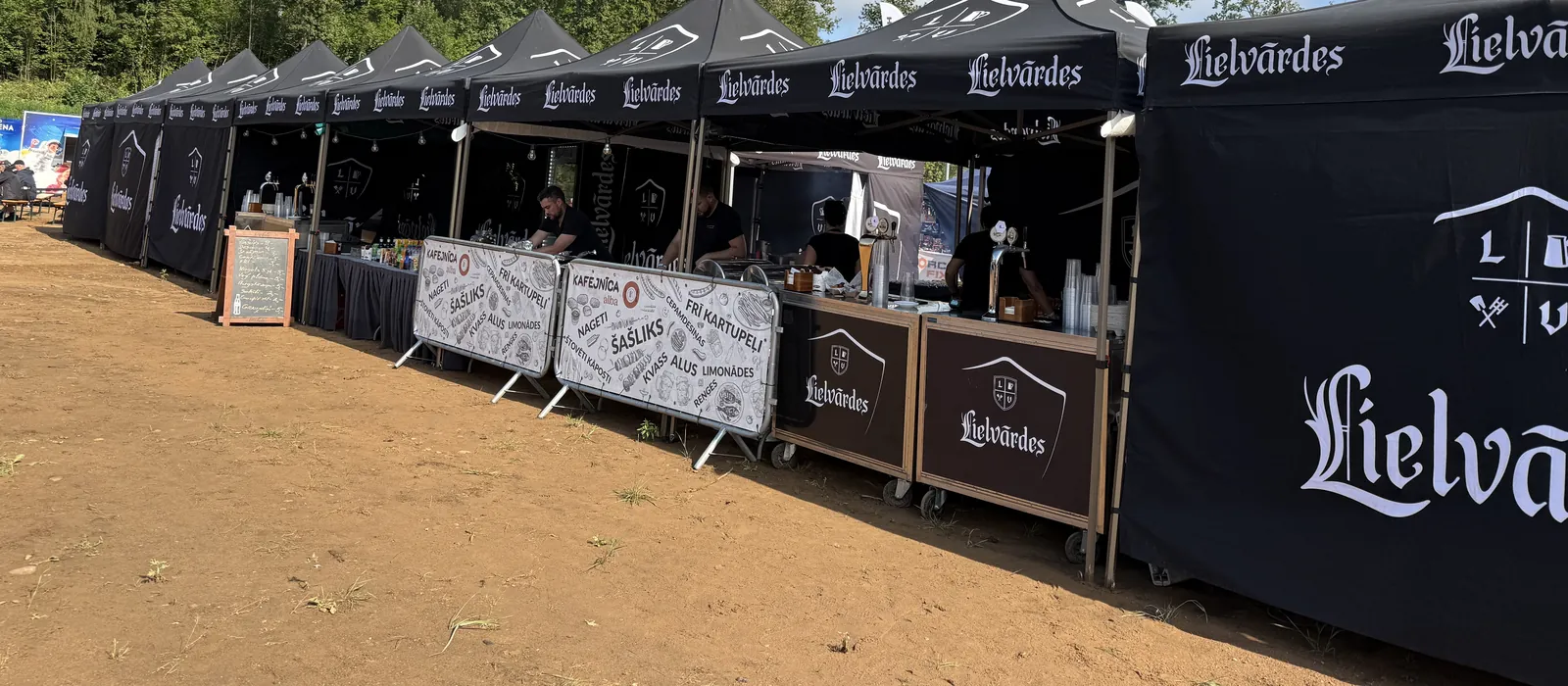 Caffe Alba tirdzniecības teltis ar ēdienkartes izkārtnēm pasākuma laukumā